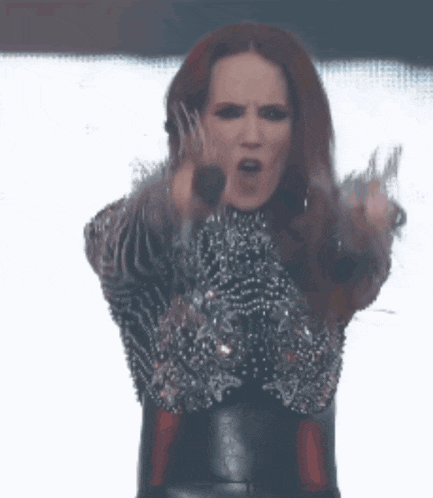 a woman with red hair is holding a microphone and pointing