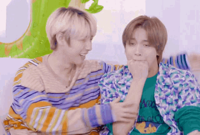 two young men are sitting next to each other on a couch and laughing .