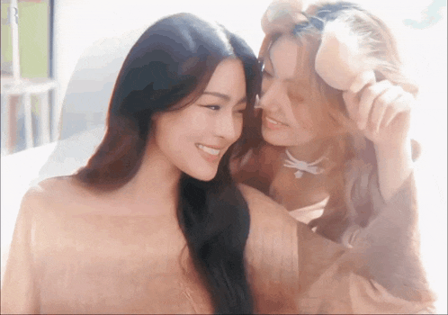 two women are looking at each other and smiling at the camera