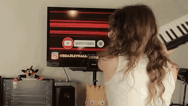 a woman is playing a keyboard in front of a tv screen that says subscribed