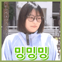 a woman wearing glasses and a blue jacket is sitting on a swing in a park .