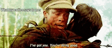 a man in a hat is hugging another man in a military uniform .