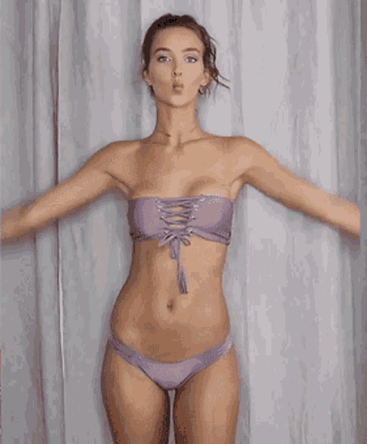 a woman in a bikini with her arms outstretched