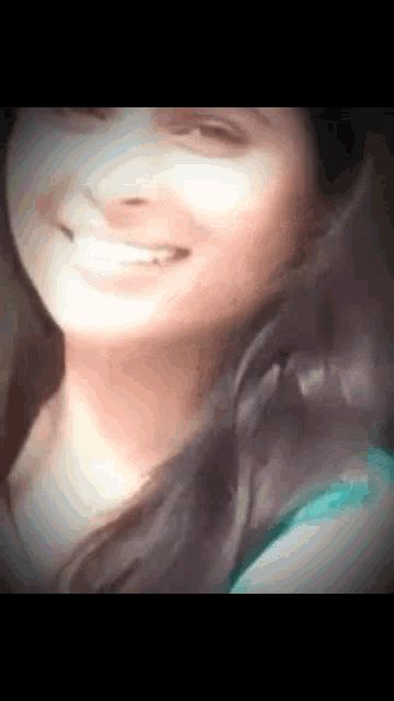a close up of a woman 's face smiling with her hair blowing in the wind .