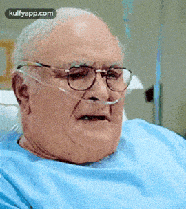 an elderly man wearing glasses is laying in a hospital bed with an oxygen tube in his nose .
