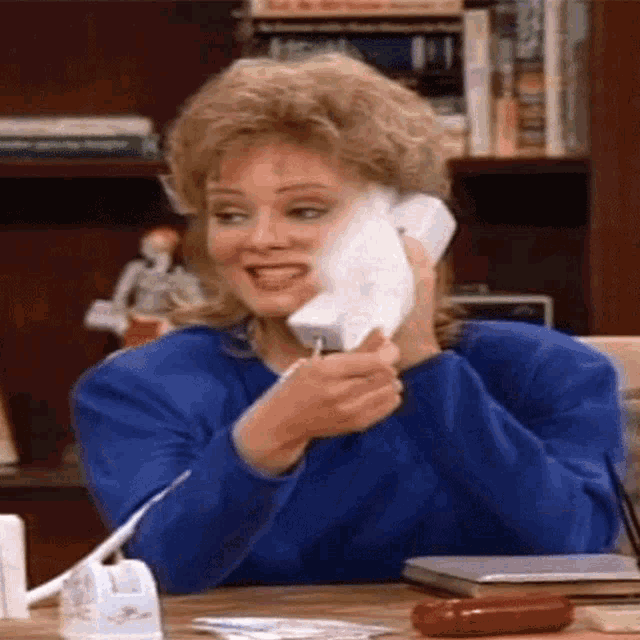 a woman in a blue sweater is talking on a phone
