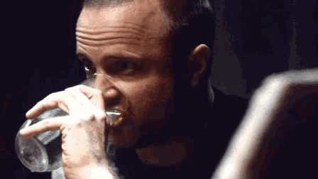 a man is drinking a glass of water from a bottle
