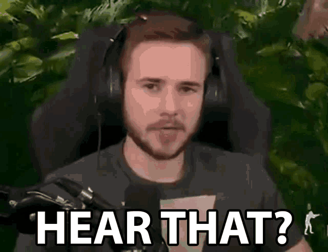 a man wearing headphones is sitting in front of a microphone and saying hear that ?