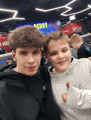 two boys are posing for a photo in front of a sign that says berry