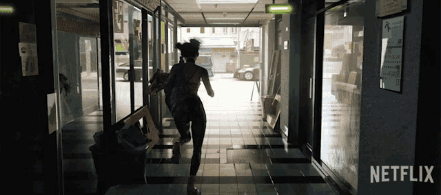 a woman is running down a hallway with a netflix logo in the corner