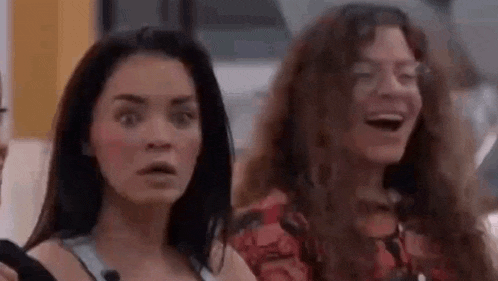 two women are standing next to each other with their mouths open and looking at the camera .