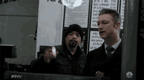 two men standing in front of a nbc sign