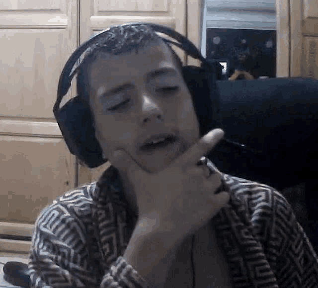 a young man wearing headphones is smoking a cigarette and making a funny face .