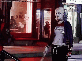 a woman in a suicide squad costume is standing in front of a red beach restaurant