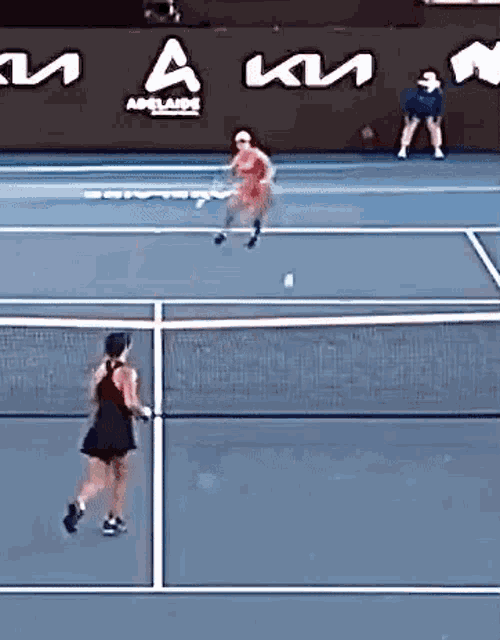 a woman in a red dress is playing tennis on a court sponsored by a kia