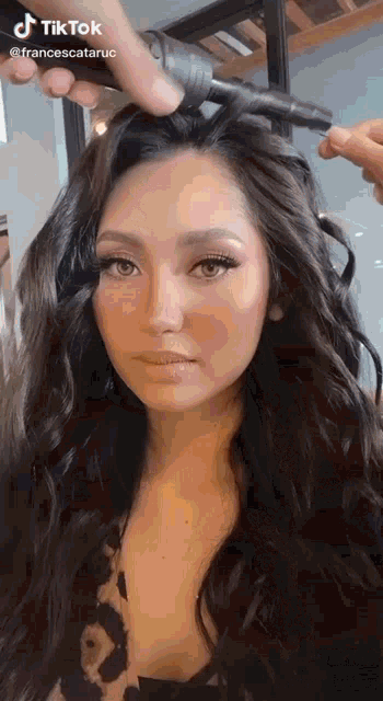 a woman with long hair is getting her hair styled by a man .