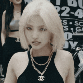 a woman wearing a black top and a gold necklace with a chanel pendant