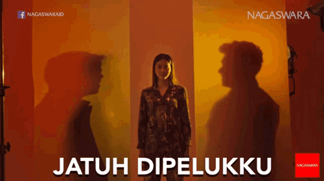 a man and a woman are standing in front of a wall with the words jatuh dipelukku written on it