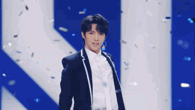 a young man in a suit and tie is standing on a stage with confetti falling around him