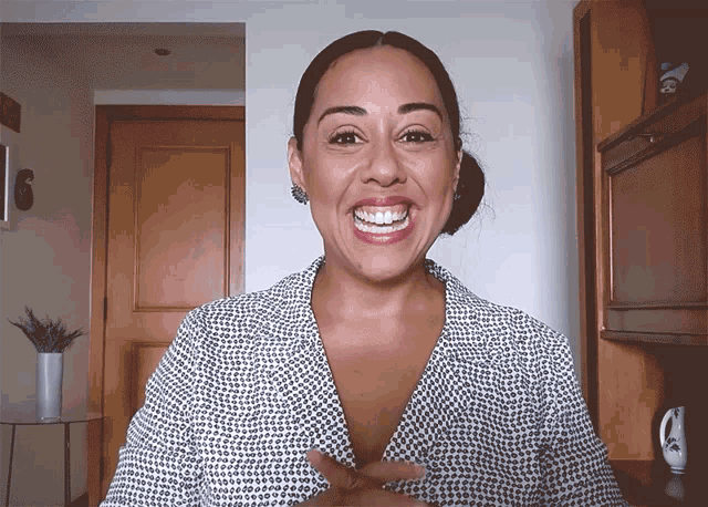 a woman is smiling and pointing at her chest
