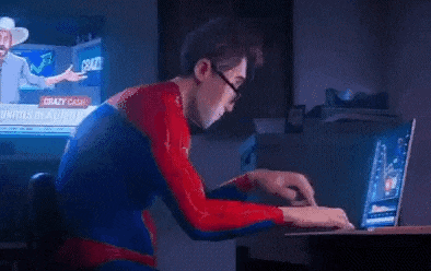 a man in a superhero costume is typing on a laptop computer .