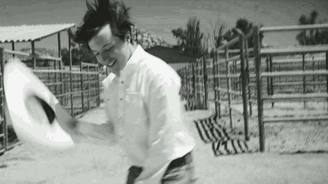 a man in a white shirt throws a cowboy hat in the air