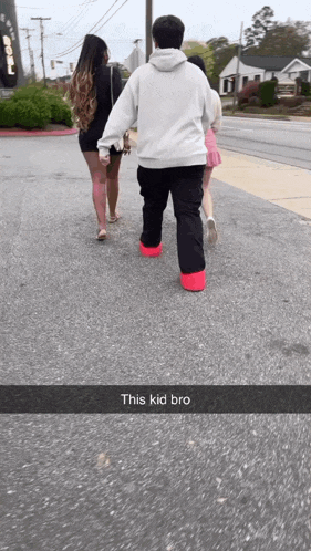 a group of people walking down a street with a caption that says " this kid bro "
