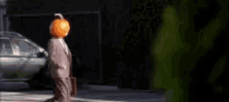 a man with a pumpkin on his head is walking down the street