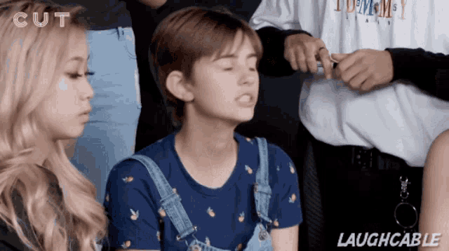 a group of people are laughing and one of them is wearing overalls
