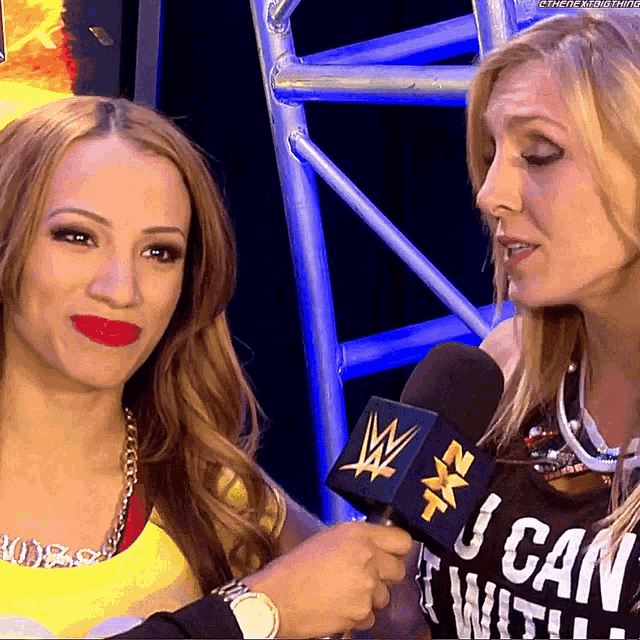 a woman wearing a black shirt that says " i can " talks into a wrestling microphone