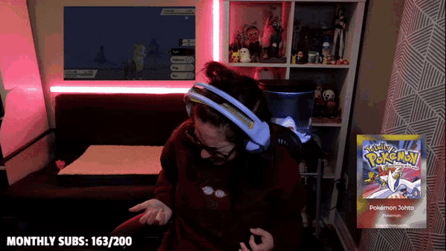 a woman wearing headphones playing a video game with a pokemon card in front of her
