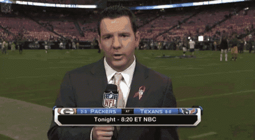 a man in a suit and tie holds a microphone in front of a nfl scoreboard