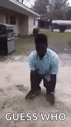 a man is kneeling down in the mud with the words `` guess who '' behind him .