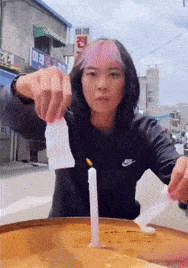 a woman in a nike sweatshirt lighting a candle