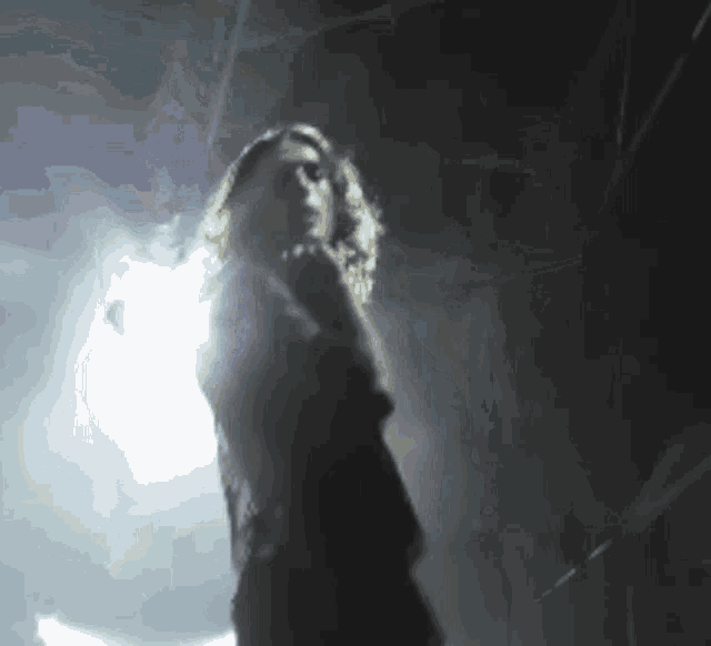 a woman in a dark room with a light shining on her