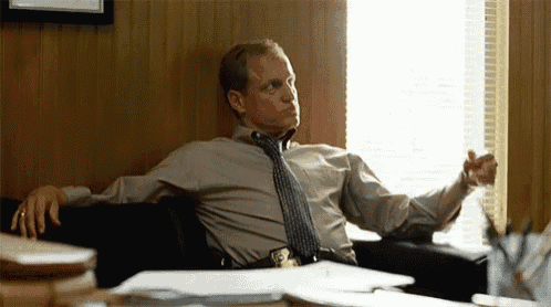 a man in a tie is sitting on a couch in front of a window