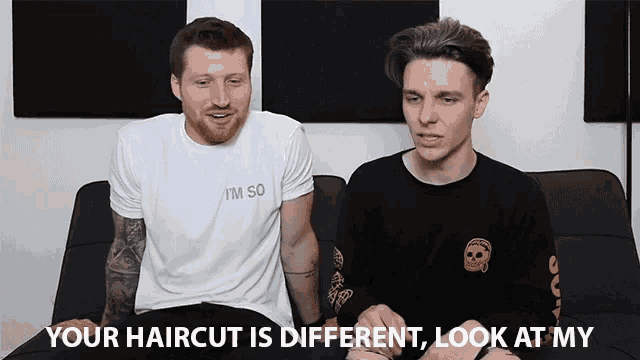 two men are sitting on a couch and one of them is wearing a shirt that says i 'm so