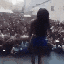 a woman is dancing on a stage in front of a crowd .