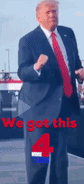 a man in a suit and tie is dancing in front of a sign that says " we got this 4 "