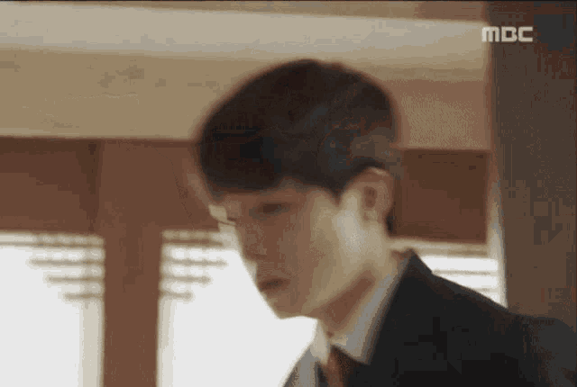 a blurry picture of a man in a suit and tie with the letters mbc on the bottom right