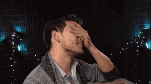 a man is covering his face with his hand .