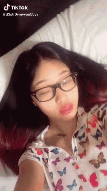 a woman wearing glasses and a shirt with butterflies on it