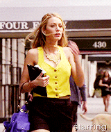 a woman in a yellow vest is walking down a street