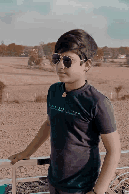 a boy wearing sunglasses and a denim revolution t-shirt