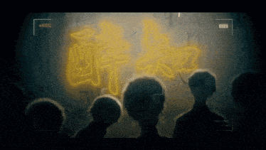 a group of people are standing in front of a wall with chinese writing on it