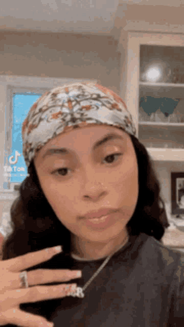 a woman wearing a head scarf and a necklace is standing in a kitchen .