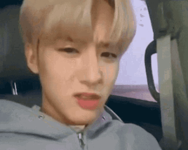 a young man is making a funny face while sitting in a car .