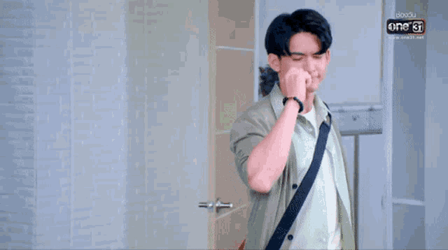 a man in a green shirt with a black bracelet on his wrist is pointing up