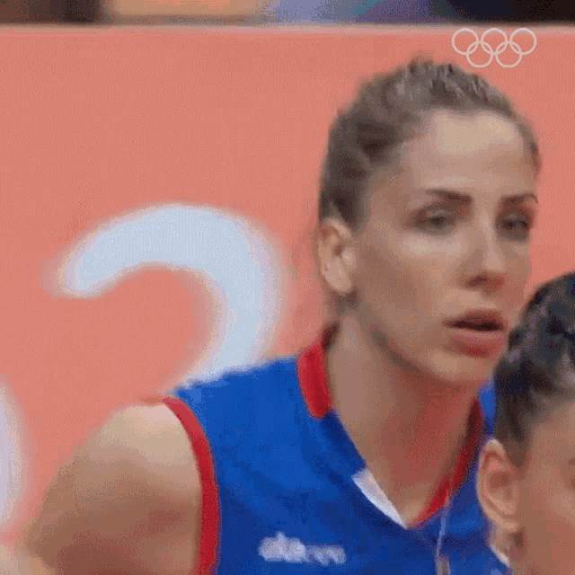 a close up of a woman 's face with the olympic rings in the background .