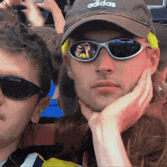 a man wearing sunglasses and an adidas hat holds his hand to his chin